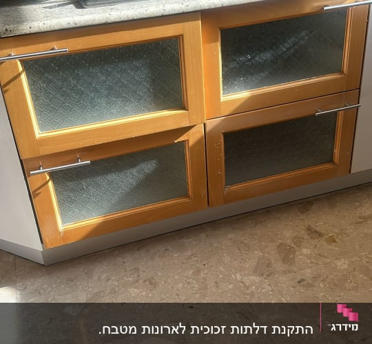 ארונות מטבח עם דלתות זכוכית ומכשירי בישול על השיש
